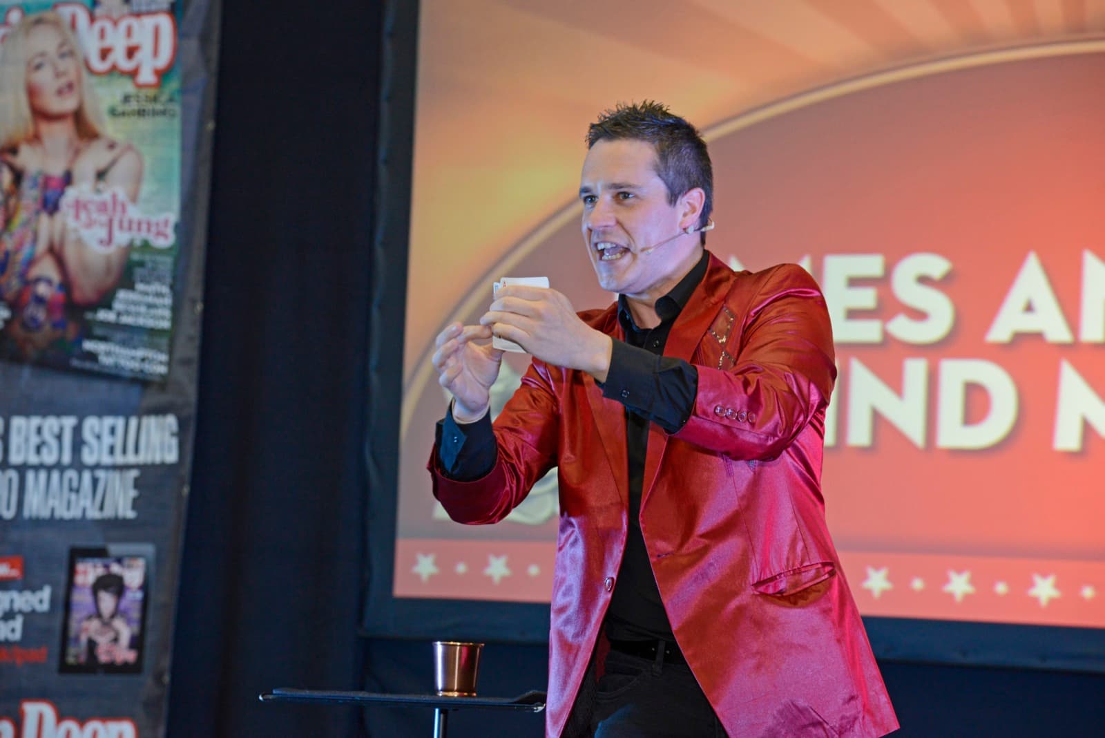 James Anthony performing mind magic on stage in a red jacket